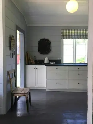 a kitchen with white cabinets and a wooden chair at Historic Timber House From The 1800S In Nordfjord in Olden