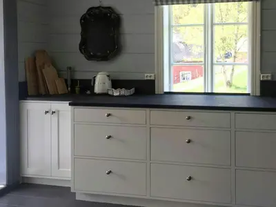 a kitchen counter with white cabinets and a window at Historic Timber House From The 1800S In Nordfjord in Olden
