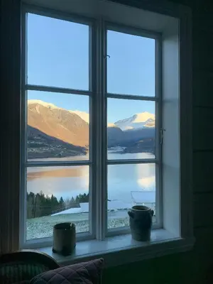 a window with a view of a lake and mountains at Historic Timber House From The 1800S In Nordfjord in Olden