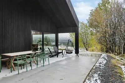 a house with a table and chairs on a patio at Stylish Cabin Near Oppdal Ski Centre in Oppdal