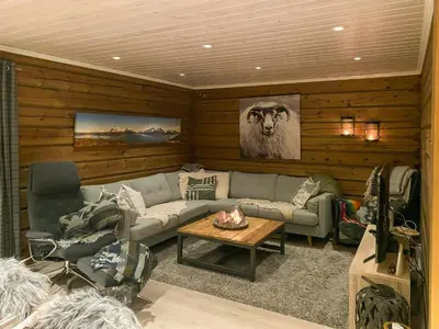 a living room with a couch and a table at Timber Cabin With Outdoor Spa Near Stranda in Brunstad