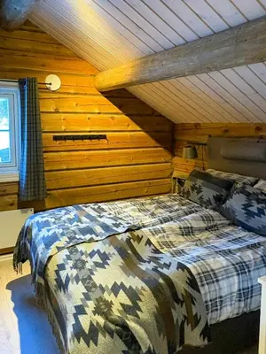 a bedroom with a bed in a room with wooden walls at Timber Cabin With Outdoor Spa Near Stranda in Brunstad