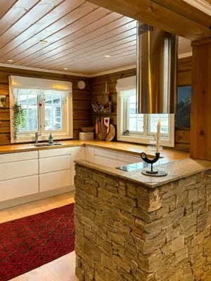 a kitchen with a stone counter top and windows at Timber Cabin With Outdoor Spa Near Stranda in Brunstad