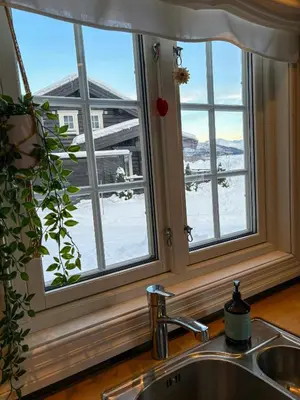 a kitchen sink with a window with a view of the snow at Timber Cabin With Outdoor Spa Near Stranda in Brunstad