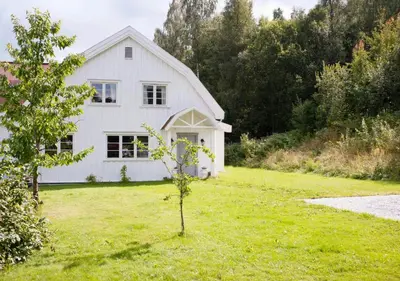 a white house with a tree in the yard at Antique House With Lake View Near Lillehammer in Fryjordet