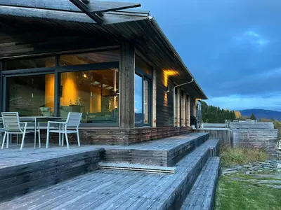 a wooden deck with a table and chairs on a house at Villa Vetleskog On Mollandsmarki In Sogn in Hafslo