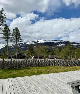 a wooden fence with snow covered mountains in the background at Modern Cabin For Large Families In Oppdal in Oppdal
