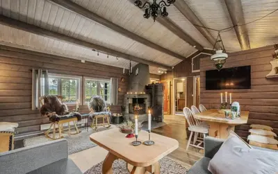 a living room with wooden walls and a table and chairs at Family-Friendly Cabin With Zipline Near Oppdal in Rennebu