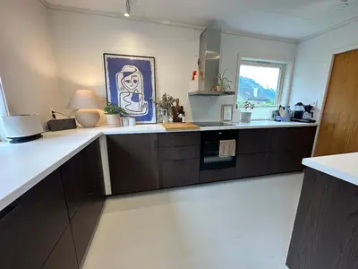a kitchen with brown cabinets and a blue painting on the wall at Perfect family house in Voss in Vossevangen