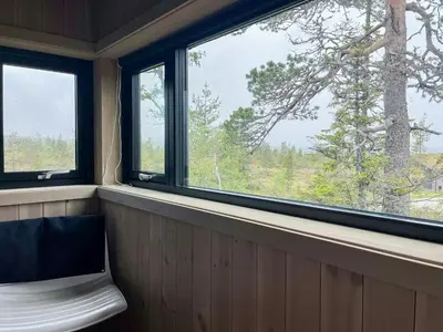 a bench in a room with two windows and a tree at Cabin At Groholsfjellet For Active Days in Veggli