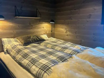 a bed in a room with a wooden wall at Cabin With Ski-Inski-Out At Stranda Ski Resort in Stranda