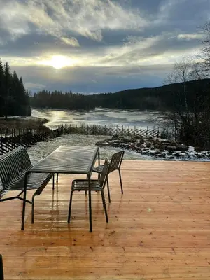 a table and two chairs on a deck with a view of a river at Architect-Designed Cabin By Lake With Sauna