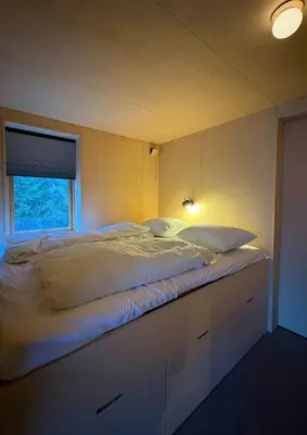 a large bed in a room with a window at Architect-Designed Cabin By Lake With Sauna