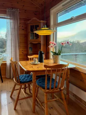 a wooden table and chairs in a room with a window at Cabin On Hilltop With Beach And Sea Views in Bekkjarvik
