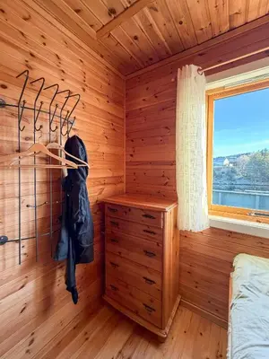 a bedroom with a wooden room with a bed and a window at Cabin On Hilltop With Beach And Sea Views in Bekkjarvik