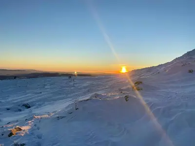 a snow covered slope with the sun setting on the horizon at Renovated Cabin On The West Side Of Trysil in Trysil