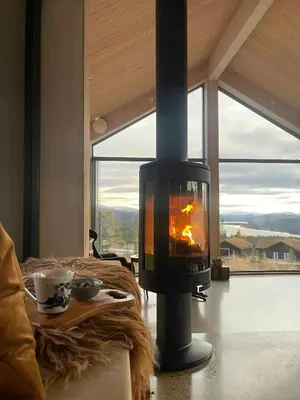 a wood burning stove in a living room with a window at Eco-Friendly Cabin With Panoramic Views In Savalen in Tynset