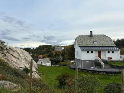 a white house on a hill with a yard at Seafront House From 1952 With Views In Veivåg in Bekkjarvik