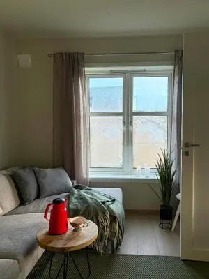 a living room with a couch and a table in front of a window at Seafront House From 1952 With Views In Veivåg in Bekkjarvik