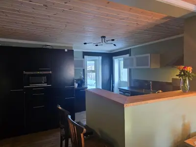 a kitchen with black cabinets and a counter with chairs at Fjellro appartment in Os