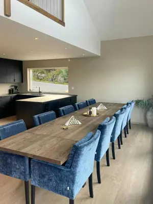 a dining room with a wooden table and blue chairs at Fisherman's Cottage With Sea Views At Kalvaneset in Steinvik