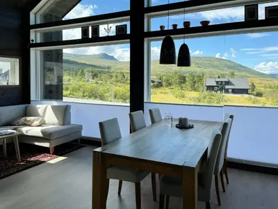 a dining room with a table and a large window at Moderne Og Koselig Hytte På Hardangervidda in Garden