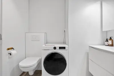 a white bathroom with a washing machine and a toilet at Central stay apartment - Rosenberg in Bergen