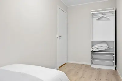 a white bedroom with a bed and a closet at Central stay apartment - Rosenberg in Bergen