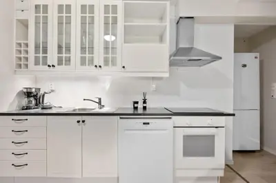 a white kitchen with white cabinets and a sink at Central stay apartment - Rosenberg in Bergen