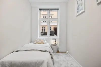 a white bedroom with a bed and a window at Central stay apartment - Rosenberg in Bergen