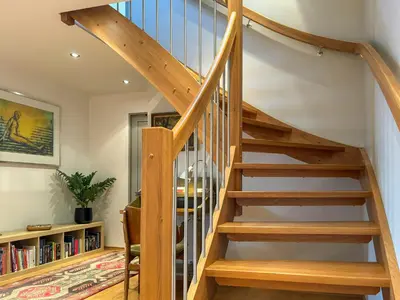 a wooden staircase in a living room with a book shelf at House With 90 Metres Private Beach On Bømlo in Ervik