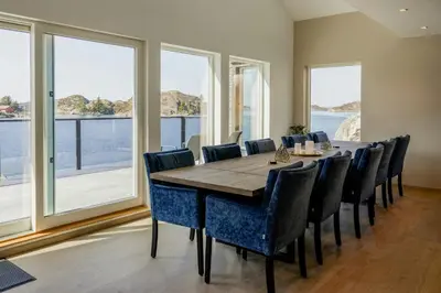 a dining room with a table and chairs and windows at Modern Fishing Cabin With Sea View At Kalvaneset in Bergen