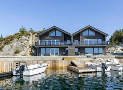 a large house with boats docked in the water at Modern Fishing Cabin With Sea View At Kalvaneset in Bergen