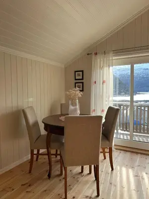 a dining room with a table and chairs and a balcony at Olastova, et koselig lite hus i nær Stryn sentrum in Stryn