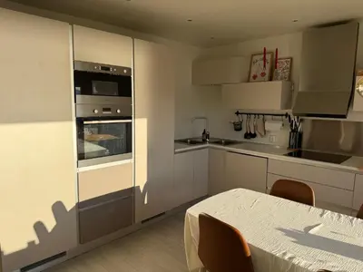 a kitchen with white cabinets and a table in it at Modern and central apartment with a view in Ålesund