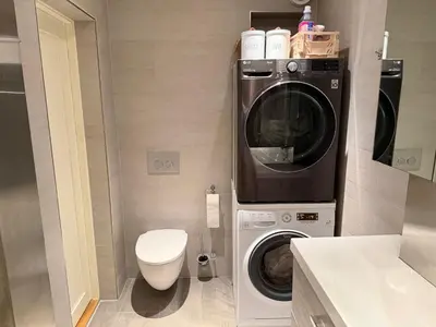 a bathroom with a washing machine and a toilet at Modern and central apartment with a view in Ålesund