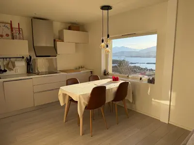 a kitchen with a table with chairs and a large window at Modern and central apartment with a view in Ålesund