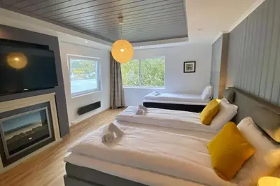 a large bedroom with two beds and a fireplace at Trolltunga Fjordview House, Odda in Odda