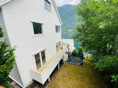 a large white house with a deck on the side of it at Trolltunga Fjordview House, Odda in Odda