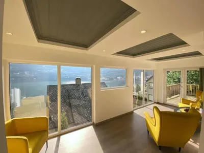 a living room with yellow chairs and large windows at Trolltunga Fjordview House, Odda in Odda