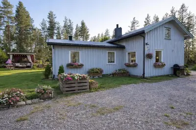 a white house with flowers in the yard at Grandma Guest House, Rena Near Ski, Biking, River summer camp in Åmot