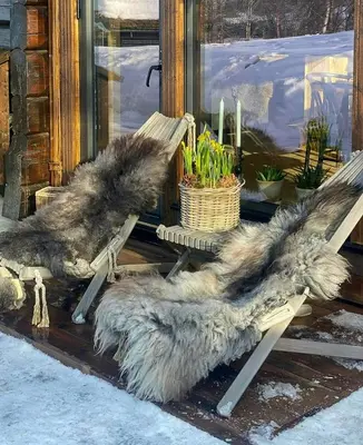 a wooden bench with a fur covered seat in front of a window at Timber Cabin With Hot Tub In Gjevilvassdalen in Oppdal