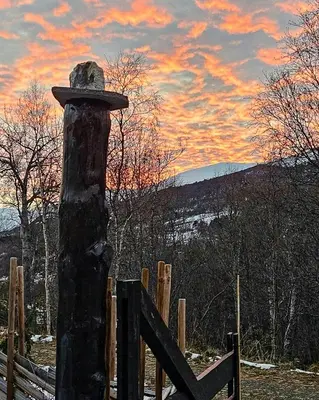 a hat on a pole next to a wooden fence at Timber Cabin With Hot Tub In Gjevilvassdalen in Oppdal