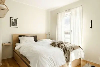 a bedroom with a bed with white sheets and a window at City apartment with balcony and 3 bedrooms! in Bergen