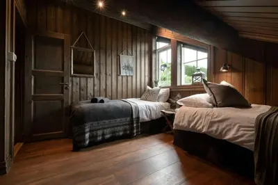 two beds in a room with wooden walls and wood floors at Large Cabin For 20 By Norefjell Ski Resort in Noresund