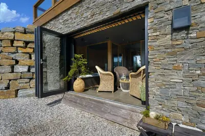 a stone house with a patio with wicker chairs at Designer Cabin For 16 With Spa In Turufjell in Flå