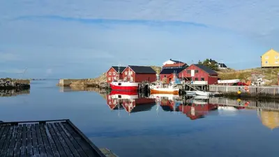 a harbor with red houses and boats in the water at Mausund- Øyperla i havet! Egen båtplass ved hytta! in Frøya