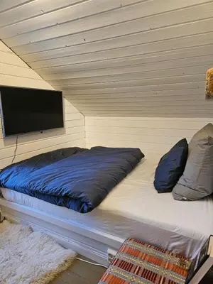 a bedroom with a bed with a flat screen tv at Mausund- Øyperla i havet! Egen båtplass ved hytta! in Frøya