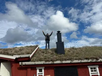 a man standing on the roof of a red house at Sits in the middle of Reinheimen and Dovrefjell Rondane in Dombås