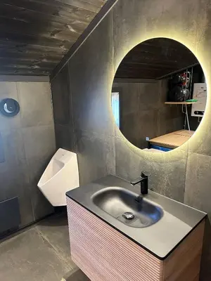 a bathroom with a sink and a circular mirror at Sits in the middle of Reinheimen and Dovrefjell Rondane in Dombås